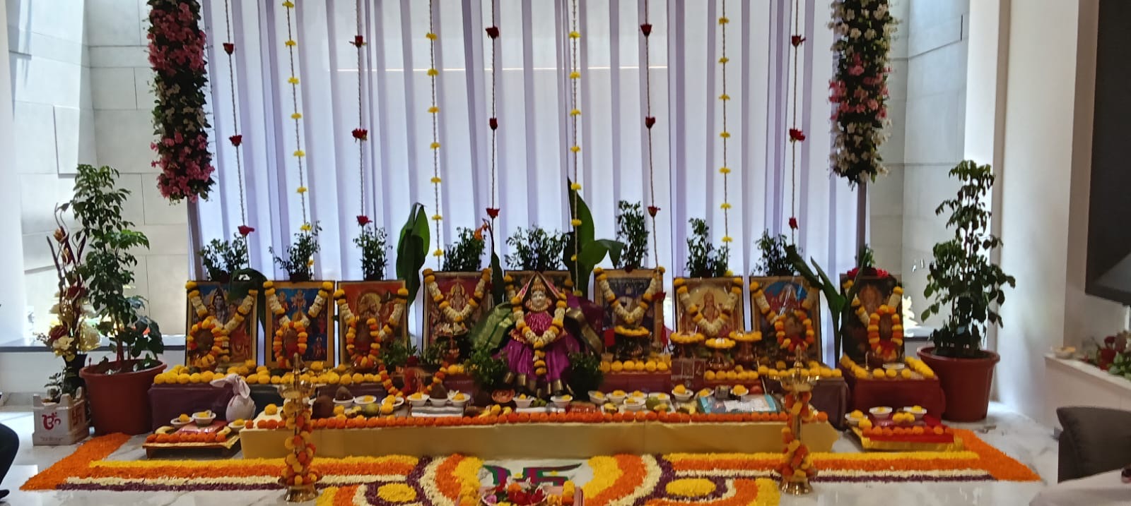 Decorated puja mandap with deity photos, marigold garlands and rangoli